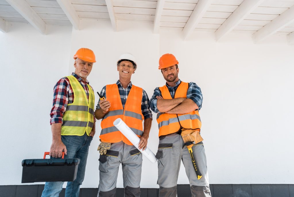 happy constructors standing with blueprint and toolbox